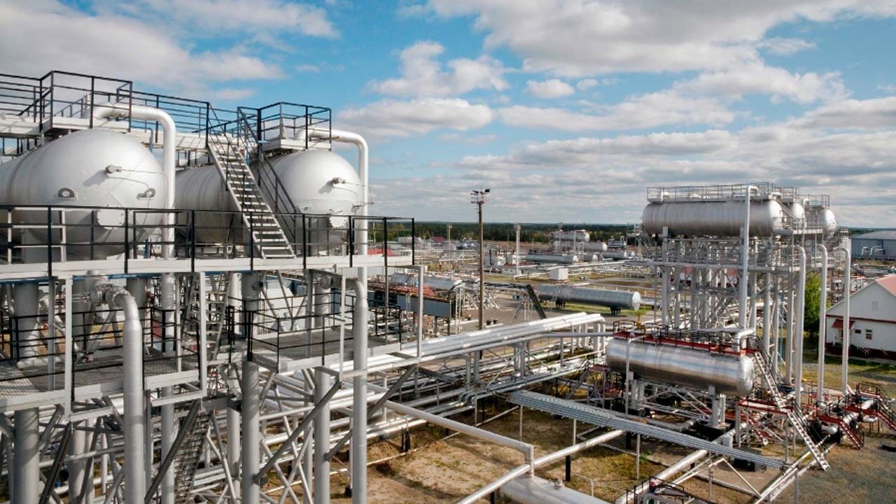 A gas processing plant in daylight: pressure vessels, pipework and steel walkways spread across an open site